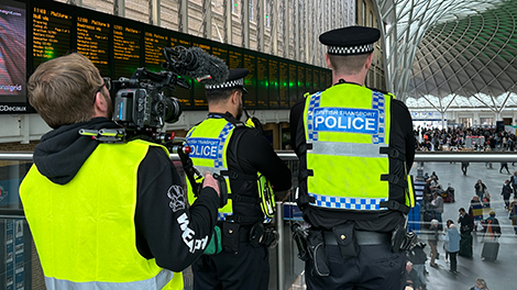 Behind the scenes of camera person filming police officers inside Kings Cross station