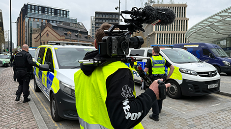 Behind the scenes of camera person filming police officers outside Kings Cross station